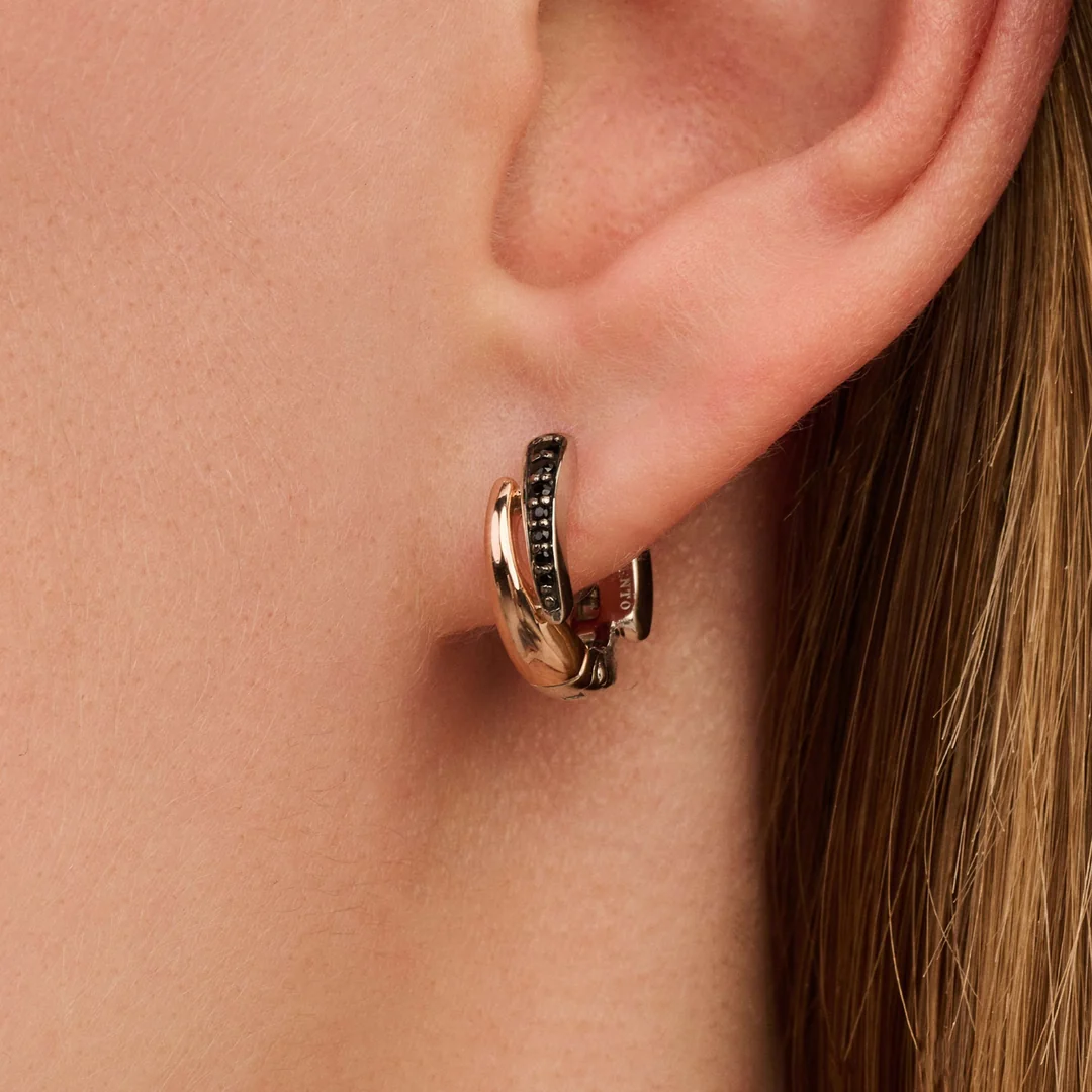 Oreille portant créoles dorées et noires entrelacées